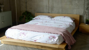 crinkle texture ruffle edged cotton bedspread in blush pink shown with blossom print duvet set