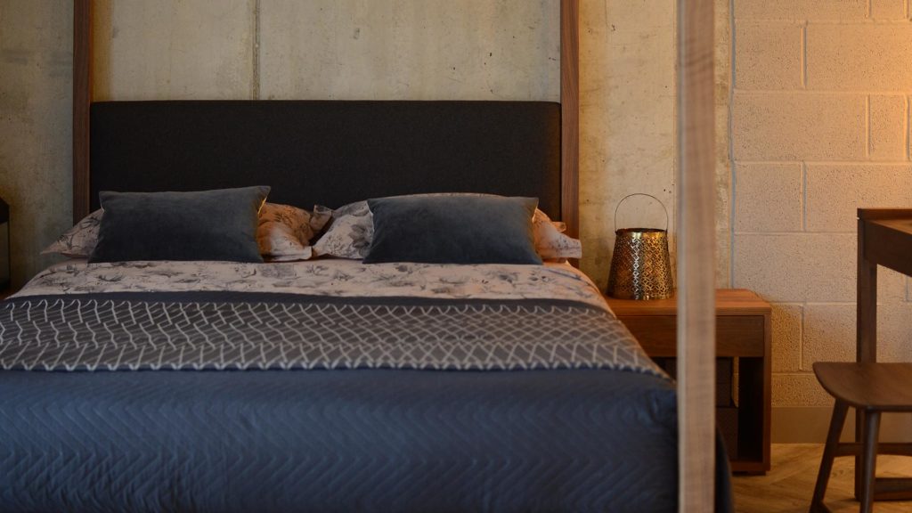 Blush pink and grey bedding with contemporary wooden 4 poster bed with upholstered headboard