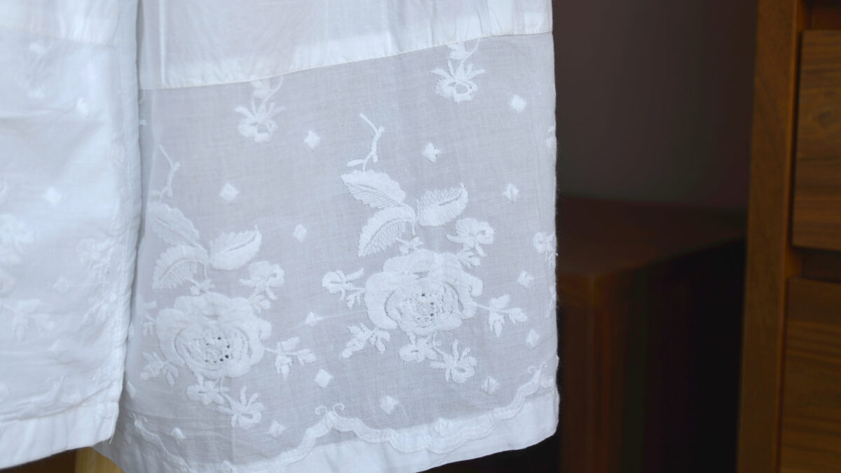 a close up of the embroidered hem of the white cotton robe